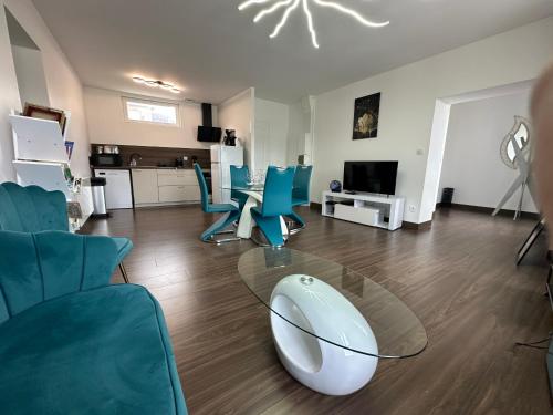 - un salon avec une table en verre et des chaises bleues dans l'établissement Captain YOO - Ginkgo Biloba - Cocon moderne sur le port, à Fécamp