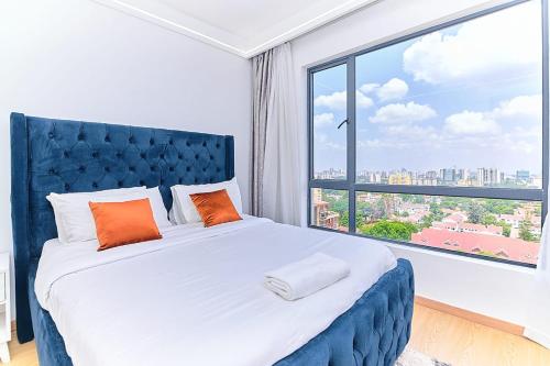 a bedroom with a blue bed with a large window at Riara One Residency, Kilimani in Nairobi