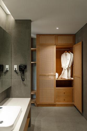 a bathroom with a sink and a robe in a cabinet at Sendoro Retreat in Láng Lớn