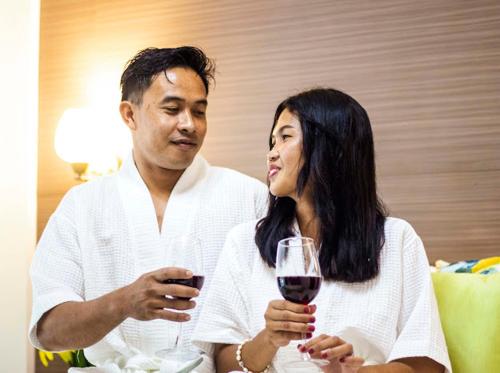 a man and a woman holding a glass of wine at Villa del Sol 1 Barkada Rooms in Guinauayan