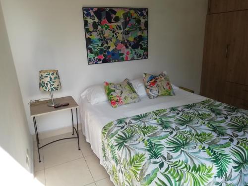 ein Schlafzimmer mit einem Bett und einem Tisch mit einer Lampe in der Unterkunft En conjunto 10 min Centro Evento Valle del Pacifico in Yumbo