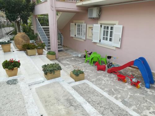 a backyard with a playground with a slide and plants at Kerannymi Family Apartment in Vouniatádes