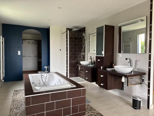 une grande salle de bain avec deux lavabos et une grande baignoire dans l'établissement Le Havre Normand Villa piscine intérieure terrain de pétanque baby foot, ping pong, table de poker, billard, terrasse aménagée, jardin, proche plages du débarquement entre Caen et Bayeux, à Coulombs