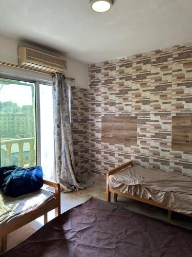 a bedroom with a brick wall and a bed and a window at استوديو صويلح studio sweileh 2 in Amman