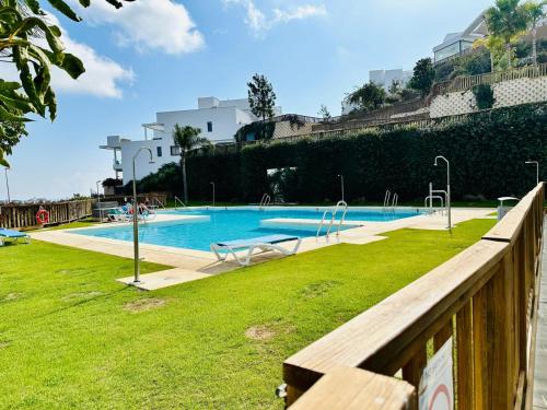 ein großer Pool mit einem Holzzaun und Gras in der Unterkunft Mijas Tres Caminos in La Cala de Mijas
