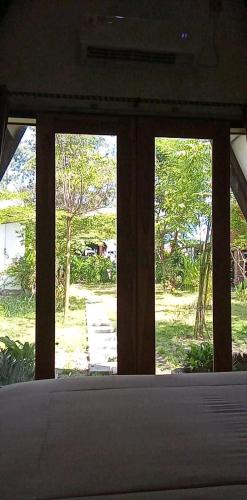 a bedroom with three windows and a view of a yard at Green cottage in Labuan Tring