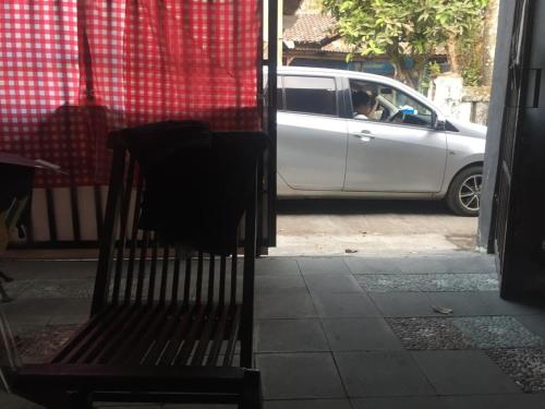 a white car is parked next to a bench at De Ikut Bojo Homestay in Magelang