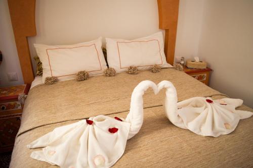 two swans dressed in white are sitting on a bed at Riad Le Khan Mogador in Essaouira