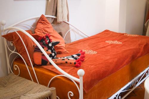 a bed with an orange comforter and pillows on it at Riad Le Khan Mogador in Essaouira