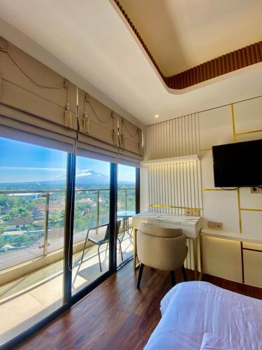 Un dormitorio con una cama y un escritorio y una gran ventana. en Apartemen Patraland Amarta, en Kejayan