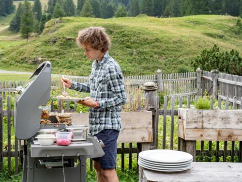 a man is preparing food on a grill at Hotel Chesa Pool in Sils Maria