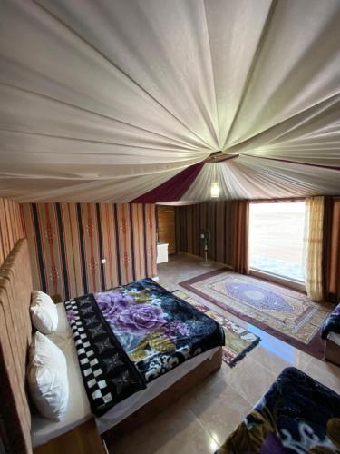 a bedroom with a bed and a large window at Rum Aranda camp & Jeep Tour in Wadi Rum