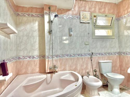 a bathroom with a tub and a toilet and a sink at Elite Apartments in Mohandseen - Families only in Cairo