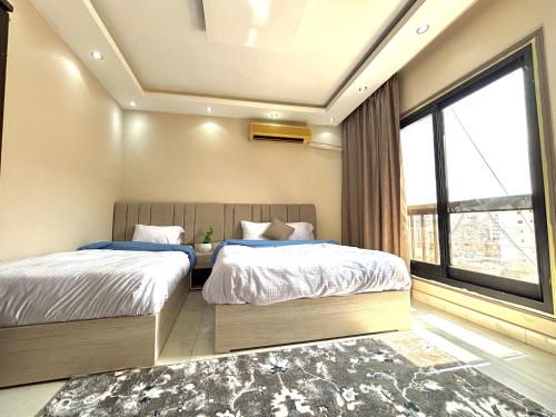 a bedroom with two beds and a large window at Elite Apartments in Mohandseen - Families only in Cairo