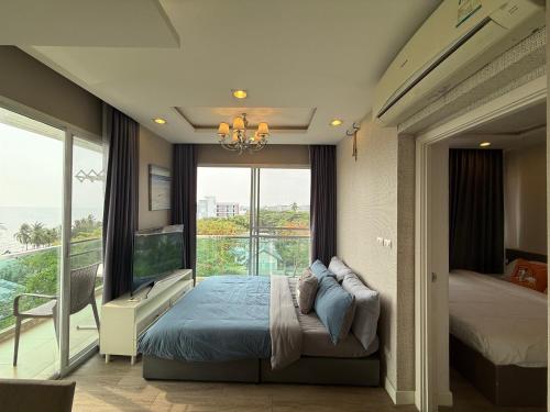 a bedroom with a bed and a large window at The Blu X Ocean view Family top floor in Ban Bang Saen (1)