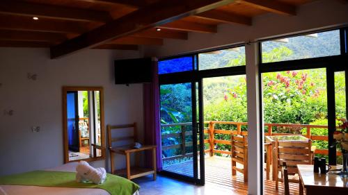 a bedroom with a large glass door and a balcony at Las Terrazas de Dana Boutique Lodge & Spa in Mindo