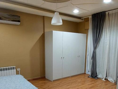a bedroom with a bed and a white cabinet at alamari gardens in Irbid