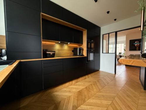 une cuisine avec des armoires noires et un plancher en bois dans l'établissement Exceptionnel 2 pieces Orangerie avec terrasse, à Strasbourg