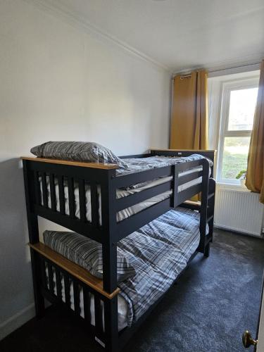 two bunk beds in a room with a window at Addex Apartment in Dunfermline