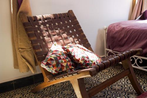 a wooden rocking chair with a pillow in a bedroom at Riad Le Khan Mogador in Essaouira