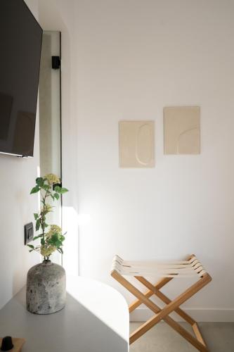 a white room with a wooden chair and a plant at Eleana Hotel in Tinos Town