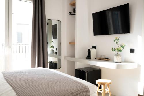 a bedroom with a bed and a tv on the wall at Eleana Hotel in Tinos Town
