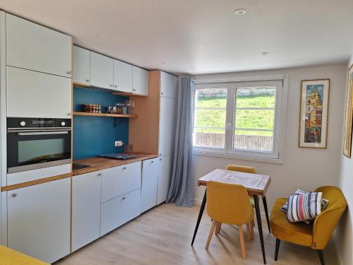 une cuisine avec des armoires blanches et une table et des chaises dans l'établissement Alpine ski apartment - Petit Châtel, à Châtel