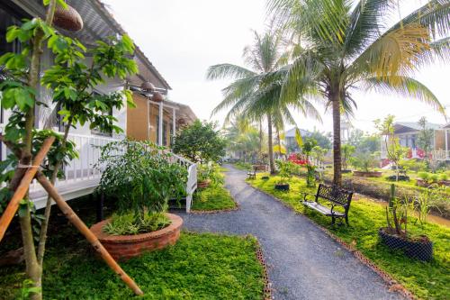 a walkway in front of a house with palm trees at Homestay Cô Hai in Xóm Rạch Già