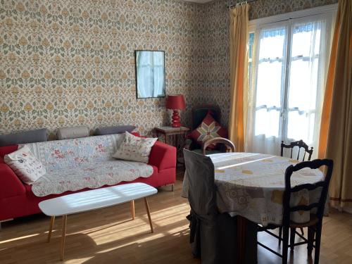 un salon avec un canapé rouge et une table dans l'établissement Maison de caractère au bord du canal du Nivernais, à Châtel-Censoir