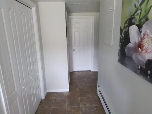 a hallway with a white door and a tile floor at Rose Valley Suites in Prince Edward Island
