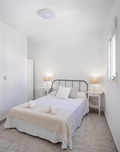 a white bedroom with a large white bed with two tables at Casco histórico de Estepona in Estepona