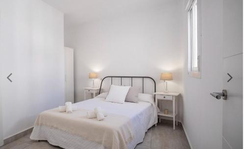 a white bedroom with a bed with two white towels on it at Casco histórico de Estepona in Estepona