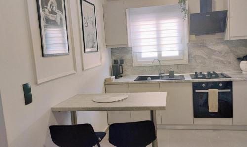 a kitchen with a table and two chairs and a sink at inas apartments 2 in Lefkímmi