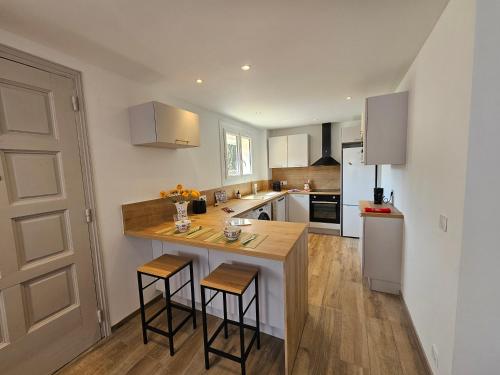 une cuisine avec un îlot et deux tabourets de bar dans l'établissement Au Farniente, à Vallauris