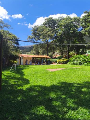 a field of grass with a building in the background at Pousada Chalés Jardim Da Serra Do Cipó in Serra do Cipo