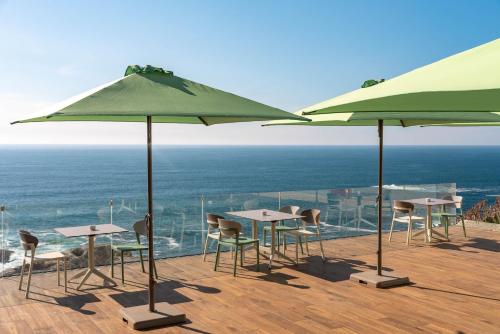 a patio with tables and chairs and umbrellas at Hotel Boutique Faro Silleiro in Baiona