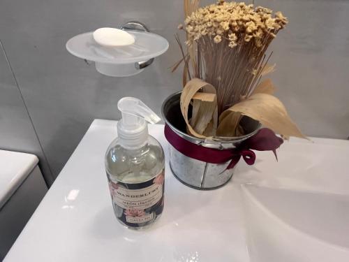 una botella de jabón y un cubo de flores en un fregadero en Suites de Portal, en Paraná