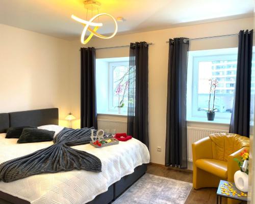a bedroom with a bed and a chair and two windows at Neubauwohnung in LINZ - sehr zentral,gratis Parkplatz und Balkon in Linz