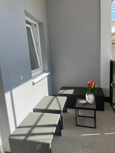 a room with two benches and a table with a vase of flowers at Neubauwohnung in LINZ - sehr zentral,gratis Parkplatz und Balkon in Linz