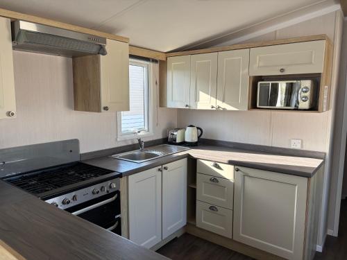 a small kitchen with white cabinets and a sink at Two bedroom Holiday Home with countryside view in St Austell