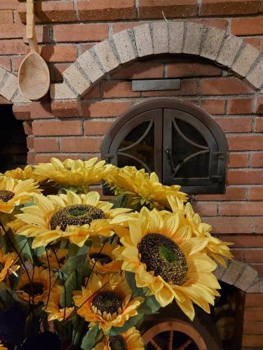 a bunch of yellow sunflowers in front of a brick wall at Pensiunea CASA MOLDOVEANA in Piatra Neamţ