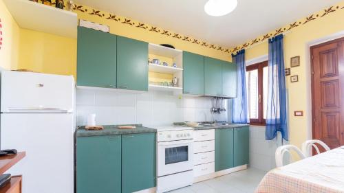 a kitchen with green cabinets and a white refrigerator at Casa Mare e Monti- Cuglieri in Cuglieri