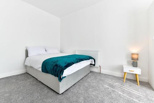 a white bedroom with a bed and a night stand at Local City Centre 3 Bedroom House in Clydach