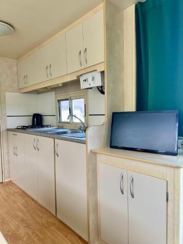 eine Küche mit weißen Schränken und einer Spüle in der Unterkunft Mobilheim Na louce II in Výrovice
