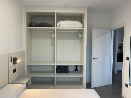 a bedroom with white shelves and a bed at Apartamentos Onzamar in Sanxenxo