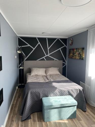 a bedroom with a bed with a blue ottoman in front of it at Vatnestrøm in Iveland