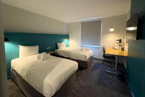 a hotel room with two beds and a desk at The Regency Hotel in Solihull