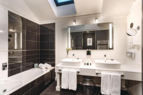 a bathroom with two sinks and a tub and a mirror at Grand Palace Brno - Czech Leading Hotels in Brno