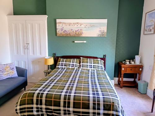 a bedroom with a bed with a plaid blanket at Bron Orme Private Hotel in Llandudno