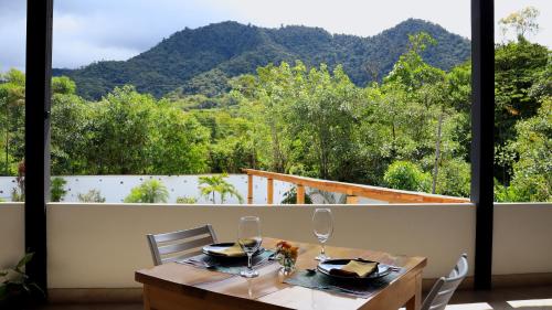 a table with wine glasses and a view of a mountain at Las Terrazas de Dana Boutique Lodge & Spa in Mindo
